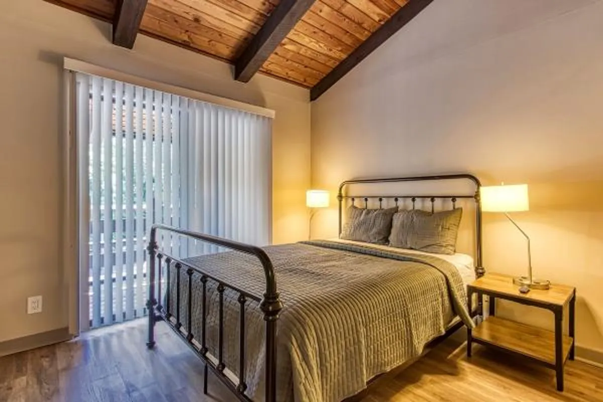 A tranquil bedroom featuring a comfortable bed with soft bedding, a nightstand, and a warm lamp casting cozy lighting. The overall atmosphere feels peaceful and perfect for unwinding after a day of adventure.